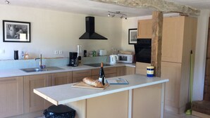 A kitchen with a central island, a black range hood, a microwave, and wooden cabinets.