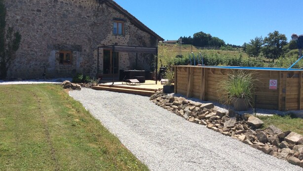 A stone building with a patio area, a pool, and a gravel path.