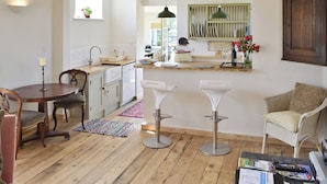 A modern kitchen with a dining area, wooden flooring, and a view of the street.