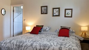 A neatly made bed with patterned bedding, two bedside lamps, and three framed pictures on the wall.