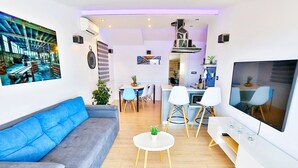A modern living room with a grey sofa, a TV, and a dining area with chairs and a table. - Apartments Ivan, (15797), Solin, hr (Solin)