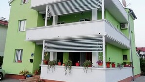 A multi-story building with balconies, potted plants, and a blue umbrella. - Apartments Kristina, (15936), Vodice, hr (Vodice)