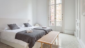 A hotel room with two beds, a bench, and a door leading to a balcony. - Spacious, very bright and centrally located apartment with AC and fiber optic Wifi (Barcelona)