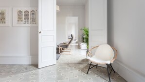 A hallway with a white door, a wicker chair, and framed architectural drawings on the wall. - Spacious, very bright and centrally located apartment with AC and fiber optic Wifi (Barcelona)