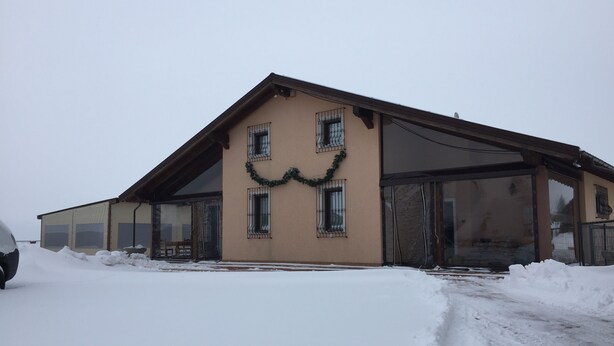 A building with a sloped roof, large windows, and a garage door.