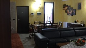 A living room with a sofa, a coffee table, and a dining area with chairs and a table.