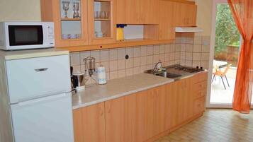 Een koelkast, een microgolfoven, kookgerei, borden en bestek