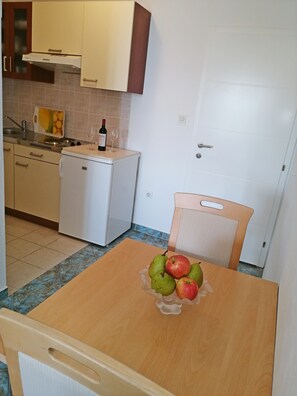 Compact kitchen with a refrigerator, microwave, and sink. Enjoy cooking and dining with a wooden table and ample storage.