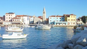 Un pueblo costero con barcos amarrados a lo largo del muelle, una iglesia con una torre destacada y edificios coloridos.