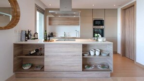 Een moderne keuken met een centraal eiland, inbouwapparatuur en een grote spiegel.