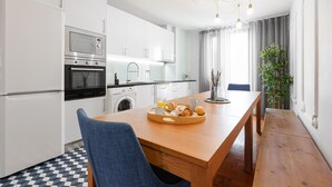 Eine moderne Küche mit weißen Schränken, einem Holzesstisch und einem Frühstücksbrettchen.