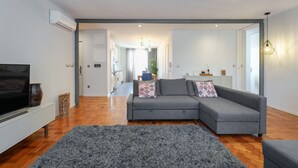 Ein modernes Wohnzimmer mit grauem Sofa, Flachbildfernseher und grauem Teppich.