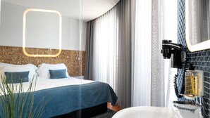 Ein modernes Hotelzimmer mit Bett, großem Spiegel, Waschbecken und Blick auf die Stadt.
