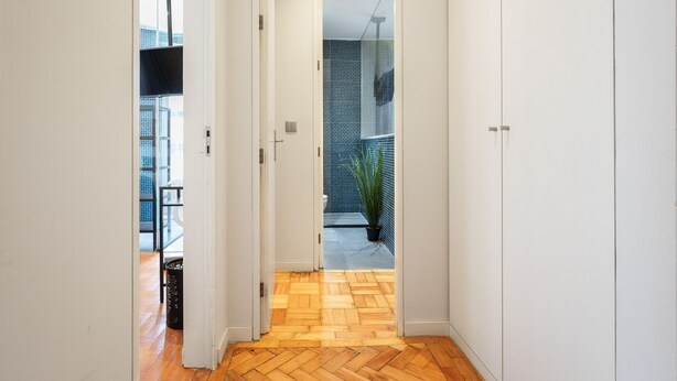 Ein Flur mit Holzboden, der zu einem Balkon mit einem Blumentopf führt.