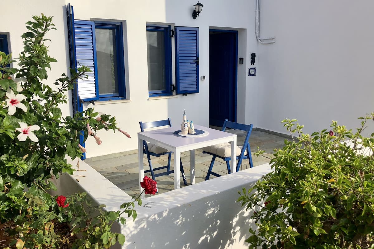 Ein weißes Gebäude mit blauen Fensterläden und einem Tisch mit Stühlen.