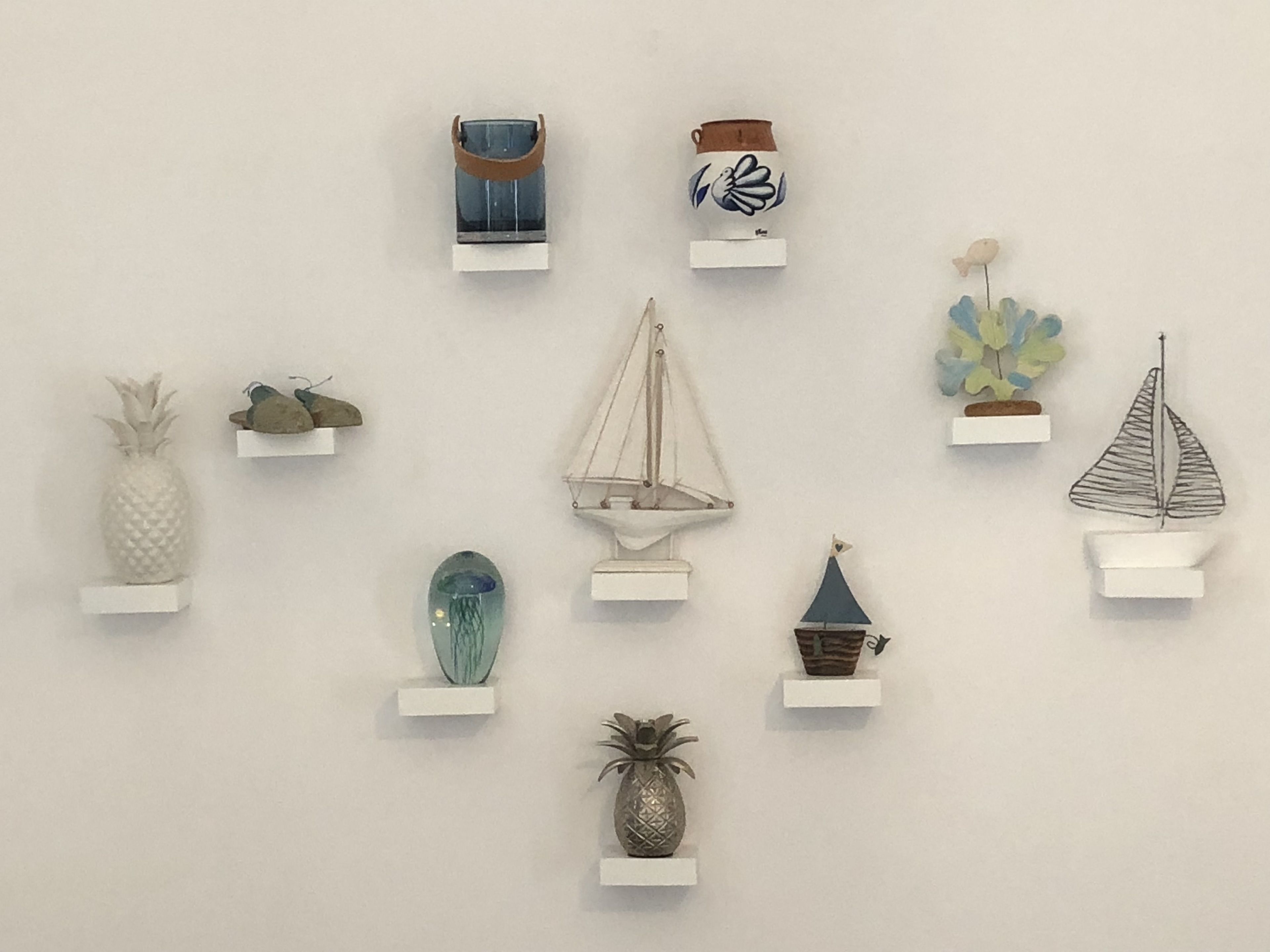 A collection of decorative items on white shelves against a plain wall.