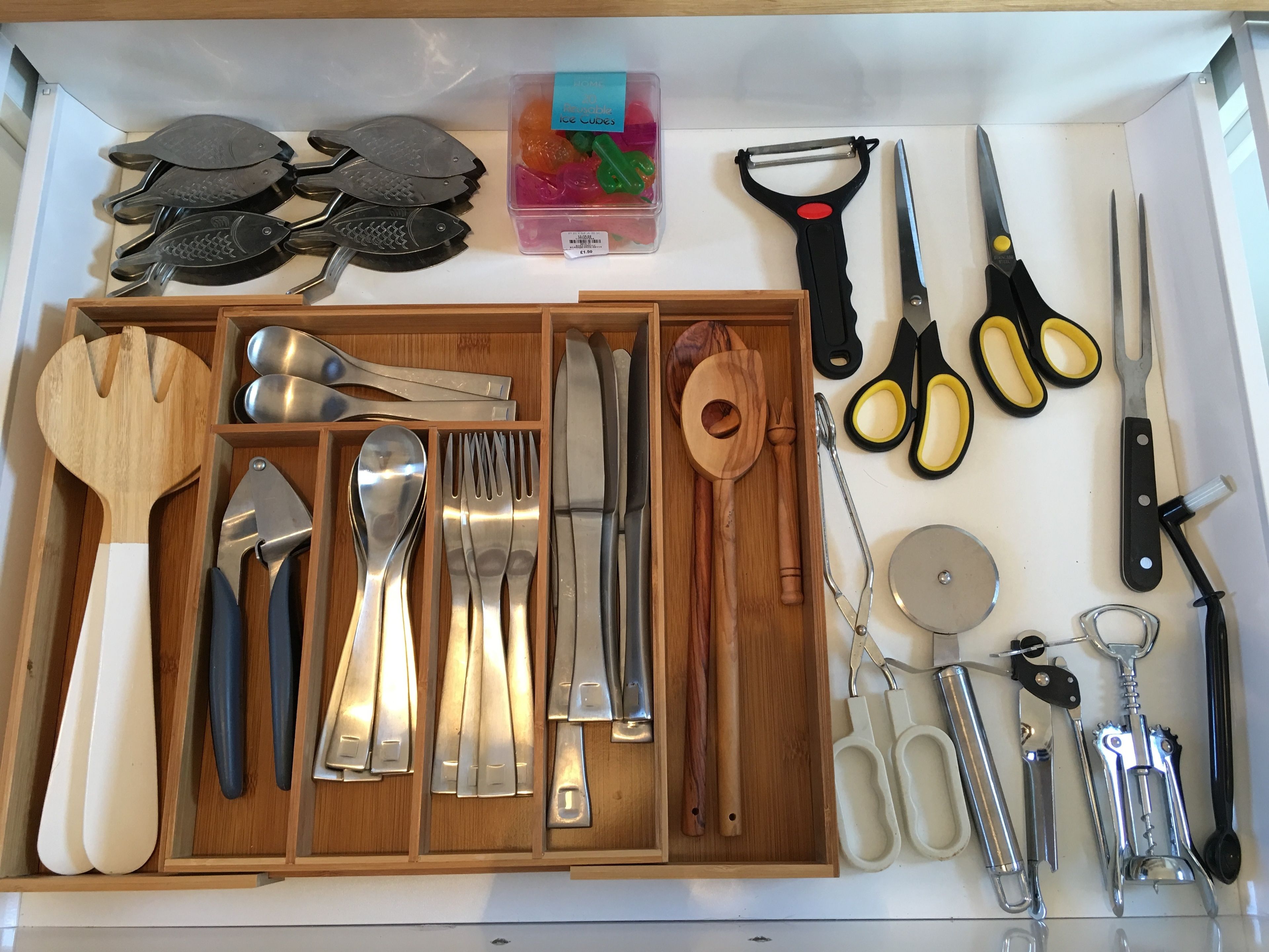 Un cajón con diversos utensilios de cocina, incluyendo espátulas, cucharas, tenedores, cuchillos y un rallador.
