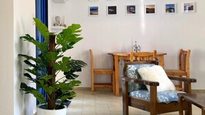 Ett vardagsrum med en matplats, en krukväxt, en väggmonterad luftkonditioneringsanläggning och en taklampa.