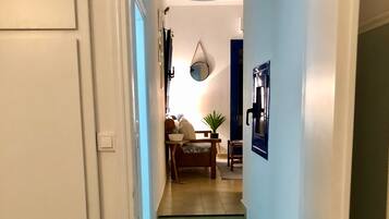 A staircase leading to a living area with a blue and white patterned rug, a hanging light fixture, and a door with a brass handle.