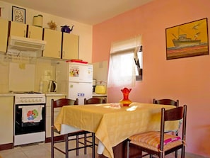 Enjoy cooking in this well-equipped kitchen with a refrigerator, stove, and sink, and dine at the adjacent table with comfortable chairs.