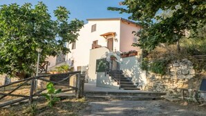 A two-story building with a stone wall and a wooden gate. - Paola Vico Equense house (Vico Equense)
