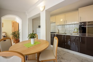 Enjoy cooking in this well-equipped kitchen with an oven and microwave, dining table for two, and potted plants.