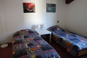 A room with two single beds, a small table, and two chairs.