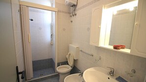 Een badkamer met twee toiletten, een wastafel, een bad en een douche.