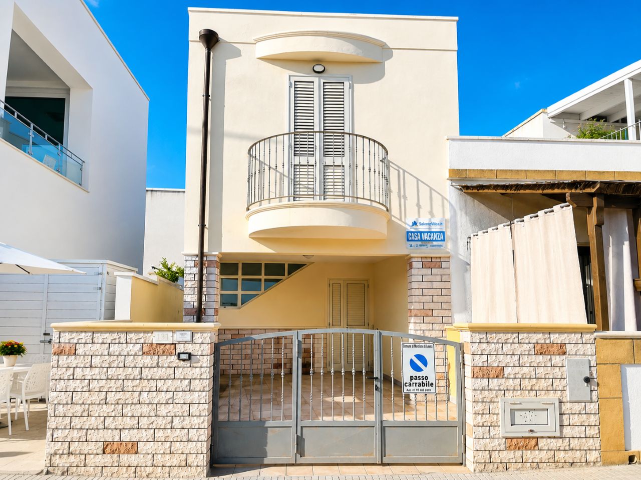 A modern building with a balcony, a gated entrance, and a sign indicating a no parking zone.