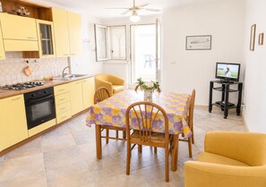 A compact kitchen with a dining area, a television, and a ceiling fan. - Detached cottage 150 meters from the sea - Maldives of Salento (Torre Vado)
