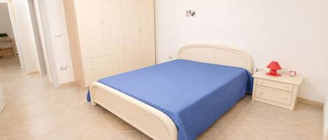 A bedroom with a bed, a wardrobe, a nightstand, and a red lamp.