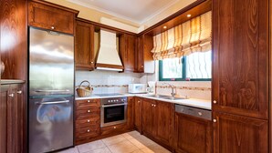 Una cocina con armarios de madera, un refrigerador de acero inoxidable, un microondas, una estufa y un lavavajillas.