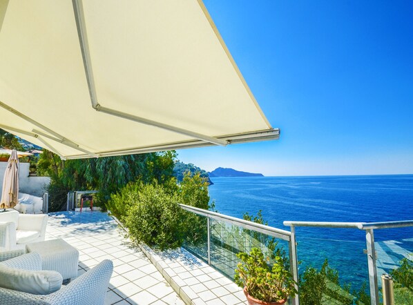 Una terraza con mobiliario exterior, una planta en maceta y vista al mar.