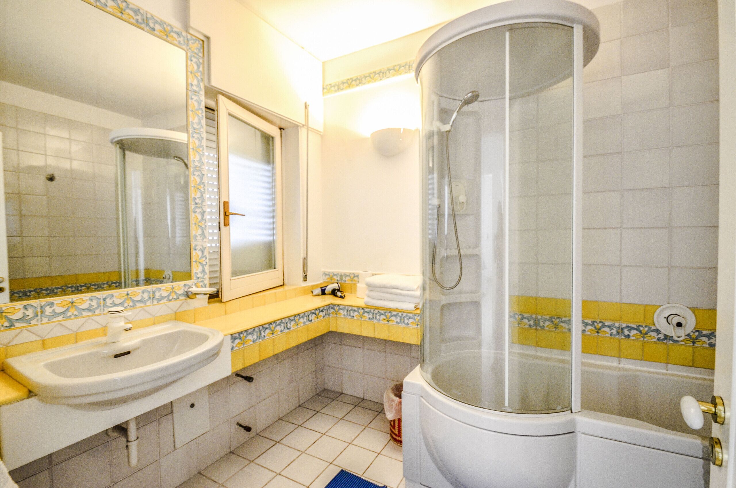 A bathroom with a sink, mirror, shower, and toilet.
