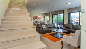 A modern living room with a staircase, a sofa set, a coffee table, and large windows offering a view of the outdoors. - Casa Oasis, Calonge - Costa Brava (Calonge)