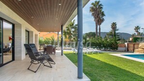 A covered patio area with lounge chairs, a pool, and a well-maintained lawn. - Casa Oasis, Calonge - Costa Brava (Calonge)