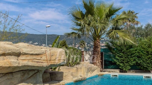 A swimming pool with a rock formation and palm trees. - Casa Oasis, Calonge - Costa Brava (Calonge)