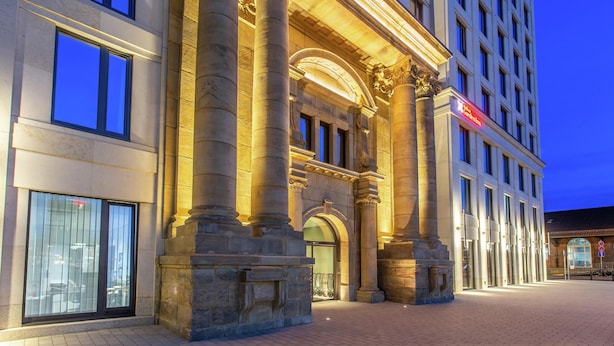 Un edificio histórico con amplias columnas, una entrada imponente y un moderno fachada de vidrio.