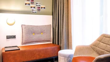 Una habitación moderna con una cama, un banco, una silla y una lámpara fijada a la pared.