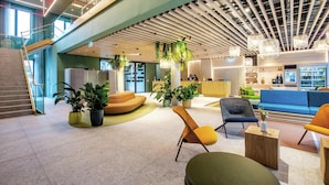 Un vestíbulo moderno con mostrador de recepción, zonas de estar y una escalera.