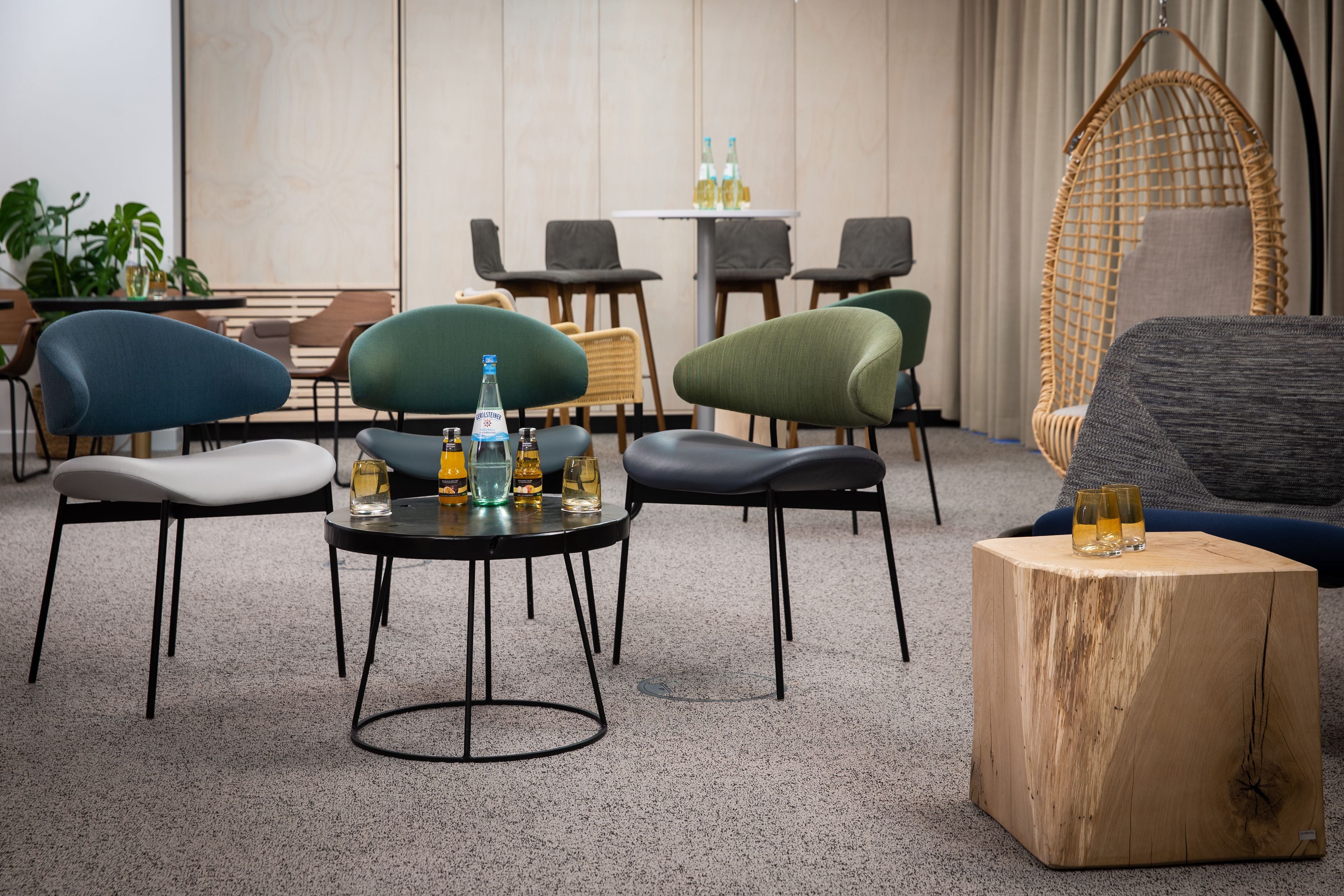 Un área de estar moderna con una mesa redonda, varias sillas y un sillón colgante.