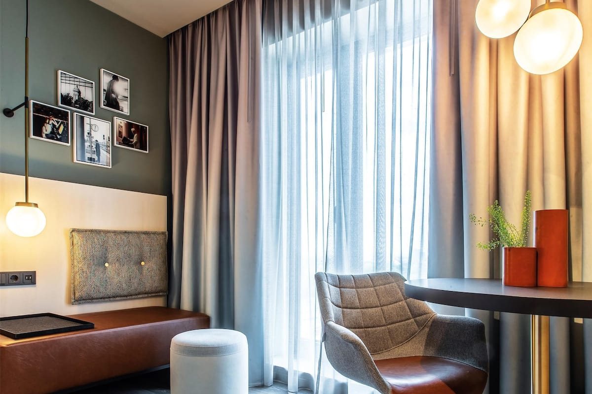 A modern room with a sofa, a chair, a table, and a hanging light fixture.