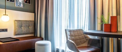 A modern room with a sofa, a chair, a table, and a hanging light fixture.