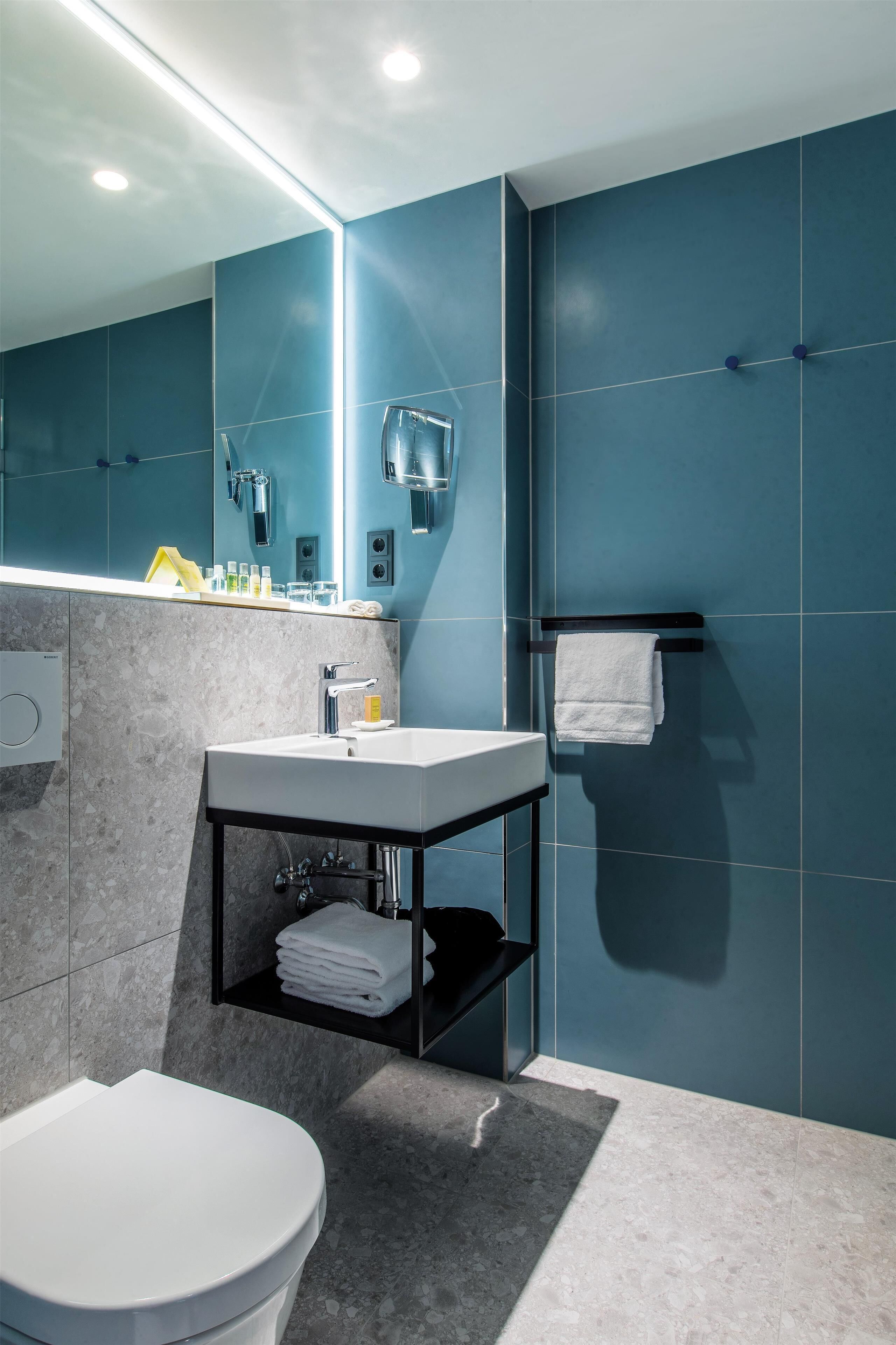 A modern bathroom with a white toilet, a sink with a mirror, and a towel rack.