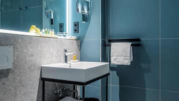 A modern bathroom with a white toilet, a sink with a mirror, and a towel rack.
