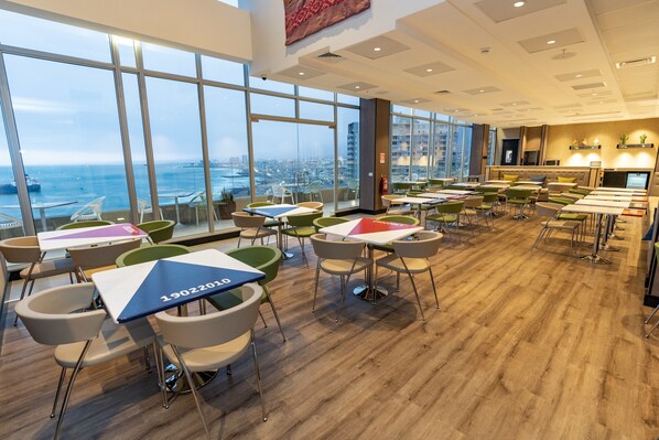 Un comedor moderno con amplios ventanales, suelo de madera y muebles contemporáneos.