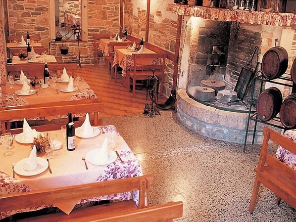 Guests can dine in style at this rustic dining area, featuring stone walls and a fireplace.