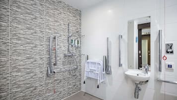 Un baño moderno con pared estampada, un lavabo, un espejo y zona de ducha.