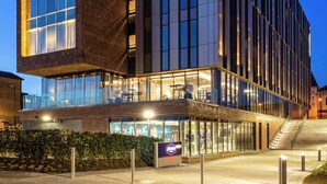 A modern hotel with a glass facade, a prominent sign, and a staircase leading to the entrance. - Hampton by Hilton Stockton on Tees (Stockton-on-Tees)