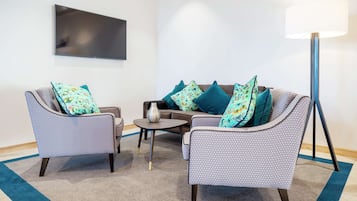 A modern living room with two patterned armchairs, a sofa, a coffee table, and a floor lamp.